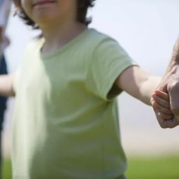 child hold two adults hands