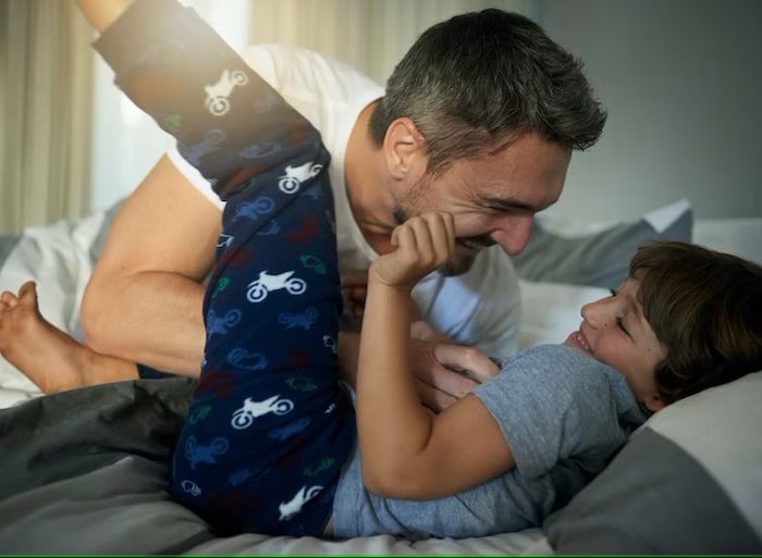 father playing with child on the bed