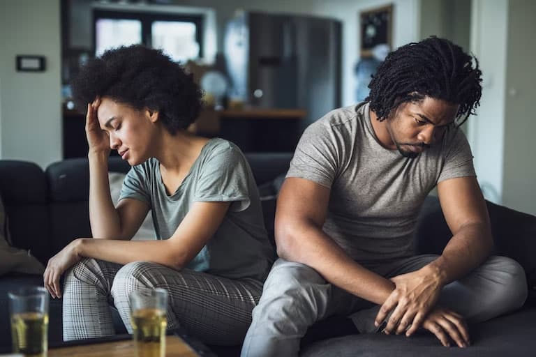 man and woman upset with each other sitting on the couch.