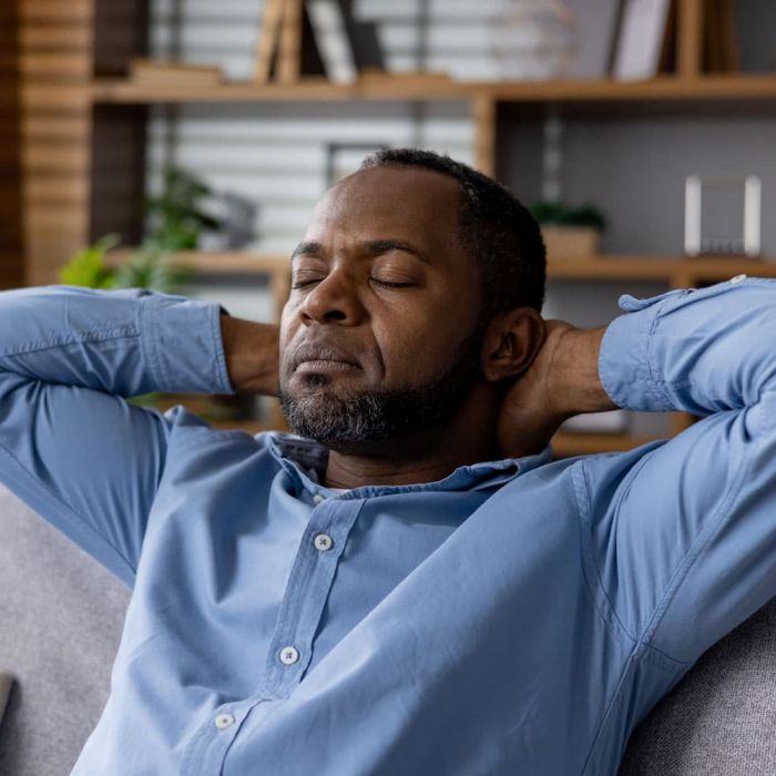 man relaxing with eyes close and arms behind his head